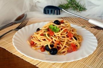 Delicious italian food spaghetti a la puttanesca on a bowl on a table.