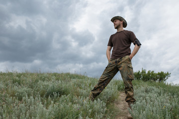 Sure man standing in field at moody sky background