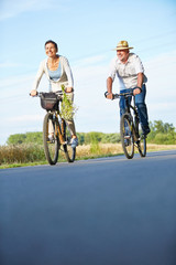 Zwei Senioren fahren Fahrrad auf Radweg