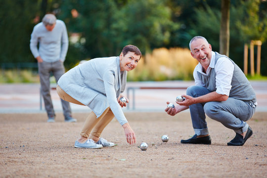 Senioren beim Boule spielen heben Kugeln auf