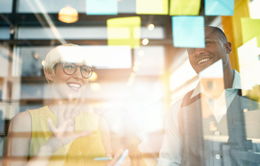 Two creative millenial small business owners working on social media strategy brainstorming using...