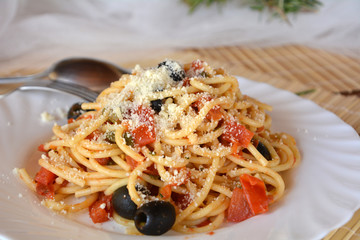 Delicious italian food spaghetti a la puttanesca on a bowl on a table.