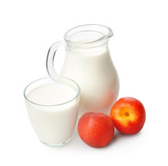 Glass of milk and jug with peaches on white