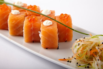 Plate of salmon sushi with lime and ginger on a white background