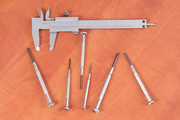 Different construction tools on a wooden background - screwdriver, caliper.