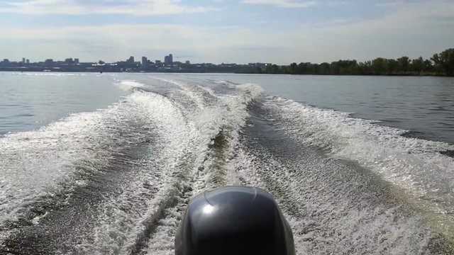 Motor boat floats on the river, waves from the engine
