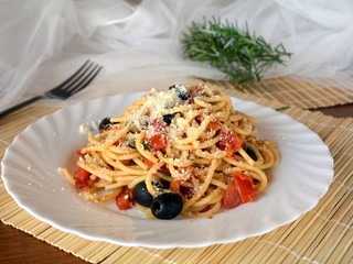 Delicious italian food spaghetti a la puttanesca on a bowl on a table.