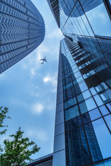 Fototapeta na wymiar plane flying over modern skyscrapers