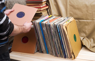 Retro styled image of a collection of old vinyl record lp's with sleeves on a wooden background. Top view.  Copy space