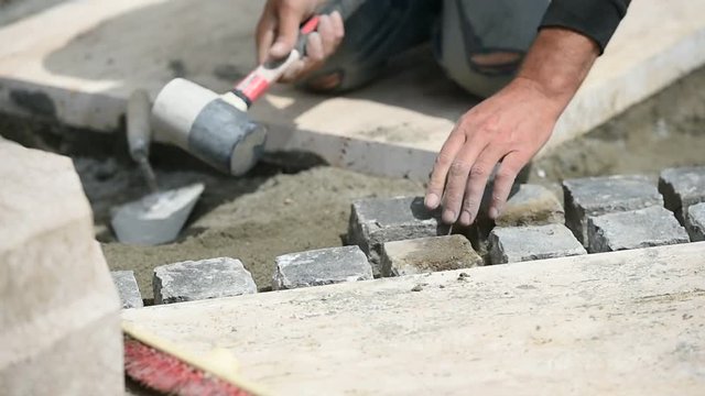 Details with hands of a mason working with cobblestone