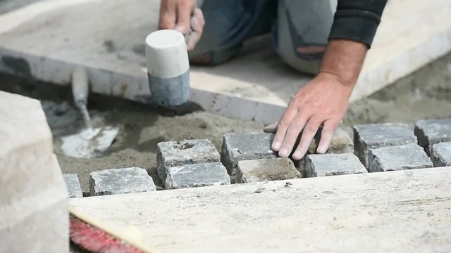 Details with hands of a mason working with cobblestone