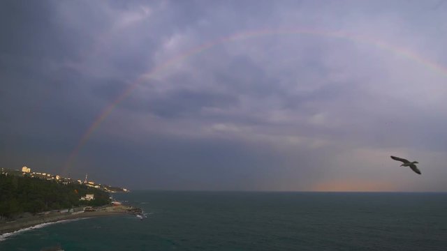 Rainbow over the sea against the backdrop of an overcast sky.
