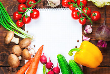 Beautiful background healthy organic eating. Studio photography the frame of different vegetables and mushrooms with a white sheet of paper on the old brown boards with free space