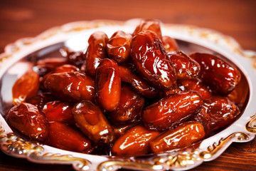 Beautiful background with dried dates on a silver tray on wooden background.  The Muslim feast of the holy month of Ramadan Kareem.