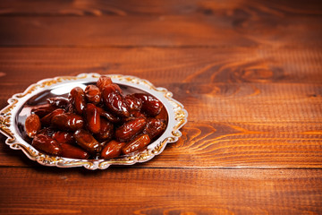 Beautiful background with dried dates on a silver tray on wooden background.  The Muslim feast of the holy month of Ramadan Kareem. Free space for your text