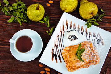 Hot chocolate along with a layer cake with pear and almonds decorated with chocolate and mint leaves