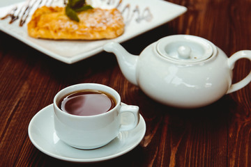 Hot chocolate along with a layer cake with pear and almonds decorated with chocolate and mint leaves