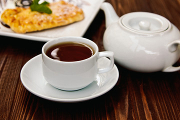 Hot chocolate along with a layer cake with pear and almonds decorated with chocolate and mint leaves