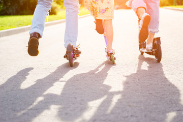 Obraz premium Parents with kid riding scooters in summer