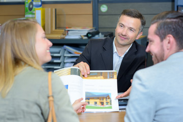 Couple looking at a housing brochure with salesman