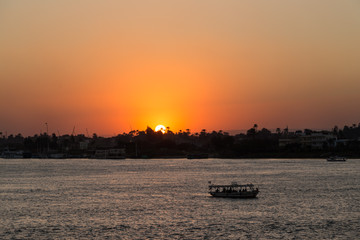 Naklejka premium Tourist boat at Luxor waterfront during sunset.