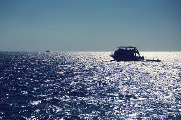 Silhouette of boat on a sea horizon.
