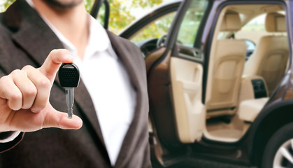 Modern car with open door and businessman holding car key