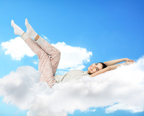 Beautiful girl lying on blue cloudy sky