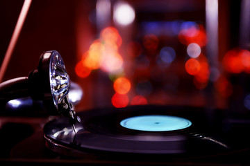 Turntable with vinyl record on dark blurred background