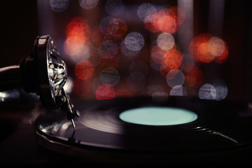 Turntable with vinyl record on dark blurred background