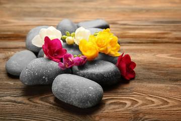 Fototapeta na wymiar Beautiful spa composition with stones and freesia on wooden background
