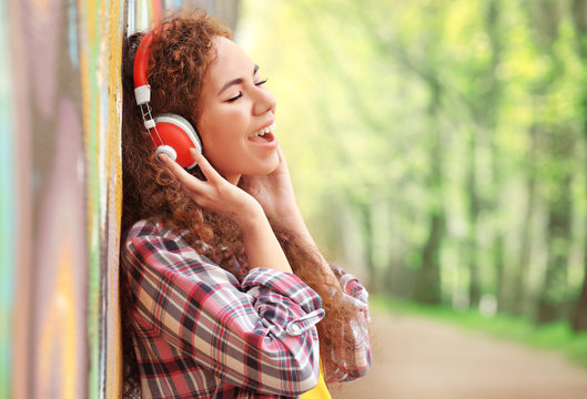 African American woman listening to music in headphones in the street