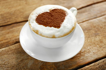 Cup of coffee with creative pattern on wooden table