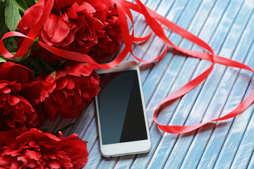 Beautiful fresh bouquet and cellphone on wooden background