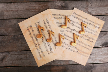 Golden music notes and sheets on wooden table, top view