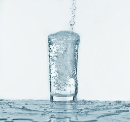Pouring water into glass on light background