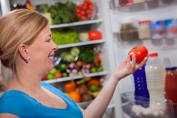 nutrition and diet  woman standing near refrigerator with fruits