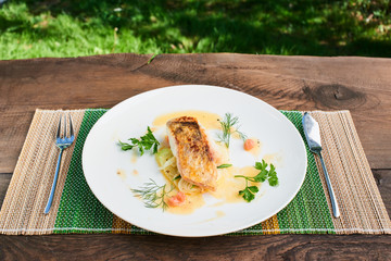 Pike perch fillet with leeks and beurre Blanc served in a white plate
