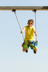 Boy playing swinging by swing-set.