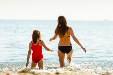 Fototapeta premium Little girl kid and woman mother in sea water. Fun