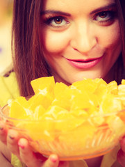 Woman holds bowl full of sliced orange fruits