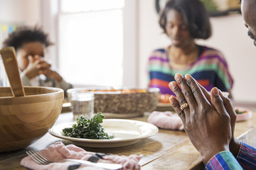 Cropped image of family saying grace at dining table
