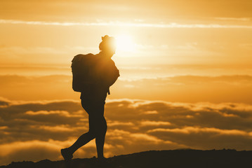 Silhouette female hiker walking on mountain during sunset