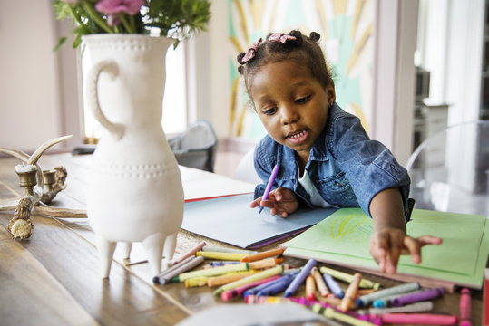 Girl choosing crayons while drawing at home