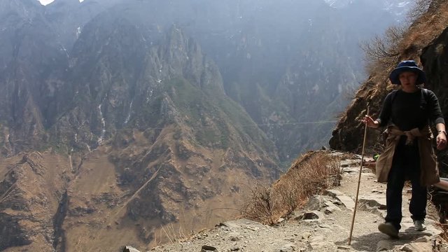Woman walking on hike trail of Tiger Leaping Gorge which is one of the deepest gorges with spectacular sceneries on the planet and has the best hiking trail in the China. 
