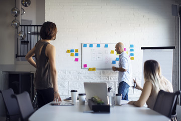 Businessman planning with female colleagues during meeting in creative office