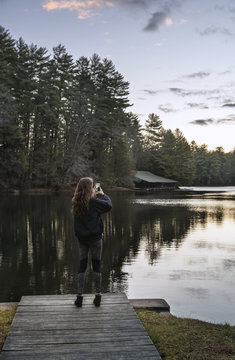 Rear view of woman photographing while standing on pier