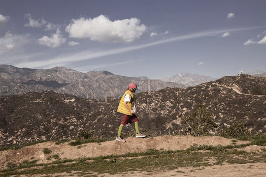 Side view of boy walking on field against mountains and sky