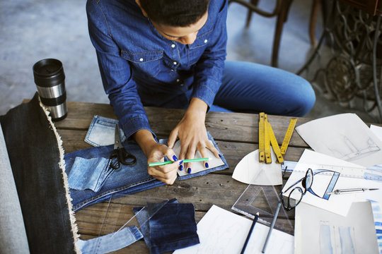 Female fashion designer marking hem on a pair of jeans