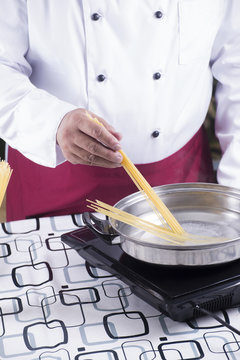 Chef putting spaghetti to boiled in the pan